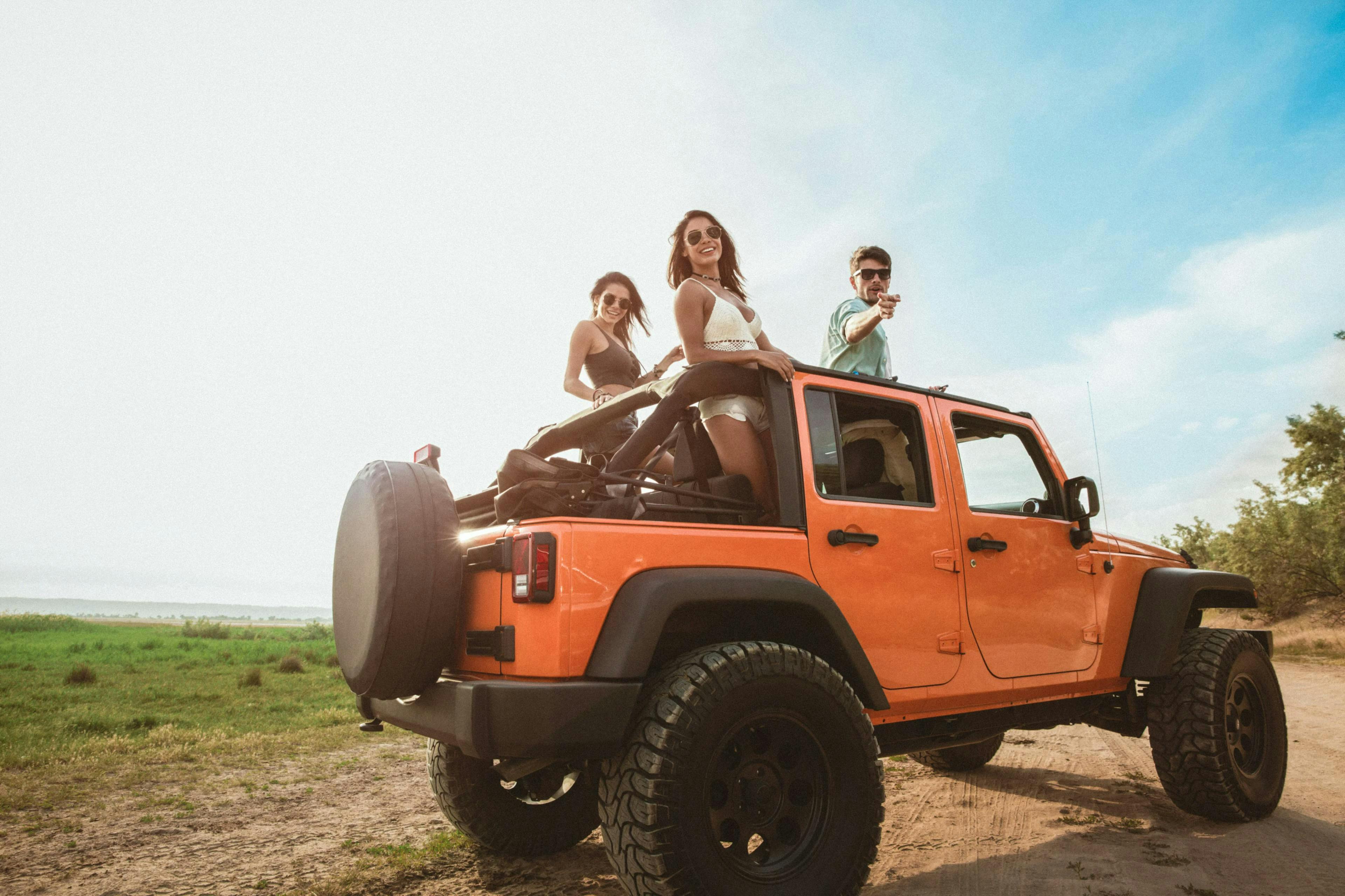 Two girls and one boy in a orange jeep