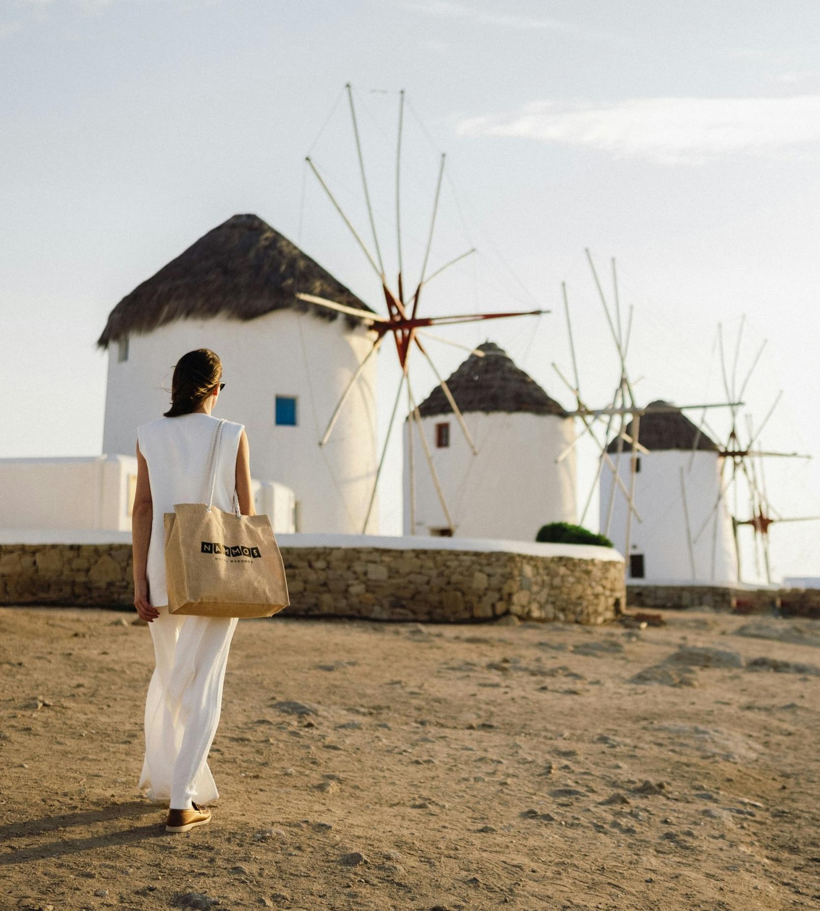 Girl walking towards windmills in Mykonos