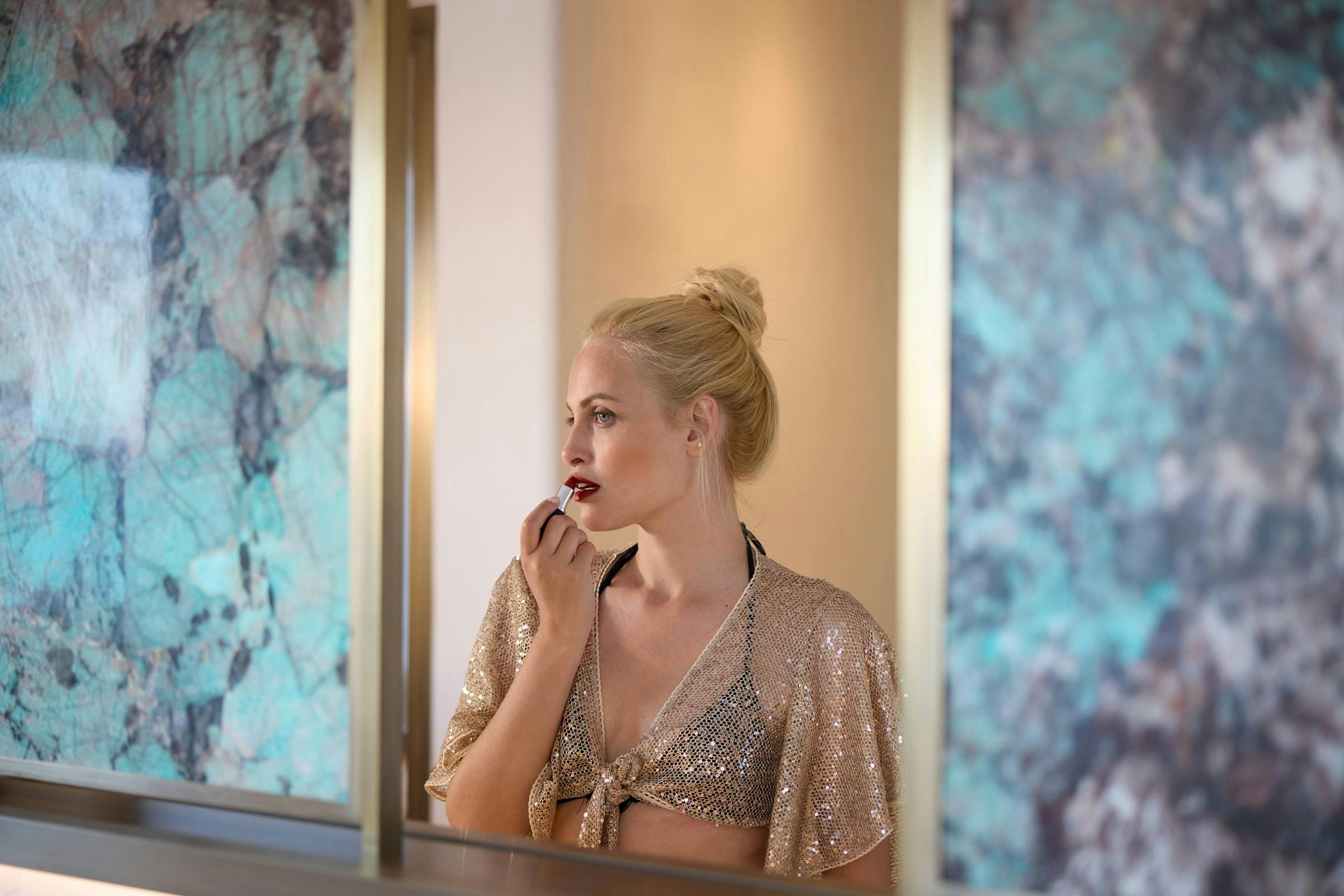 Woman putting on lipstick in a luxury interior design setting