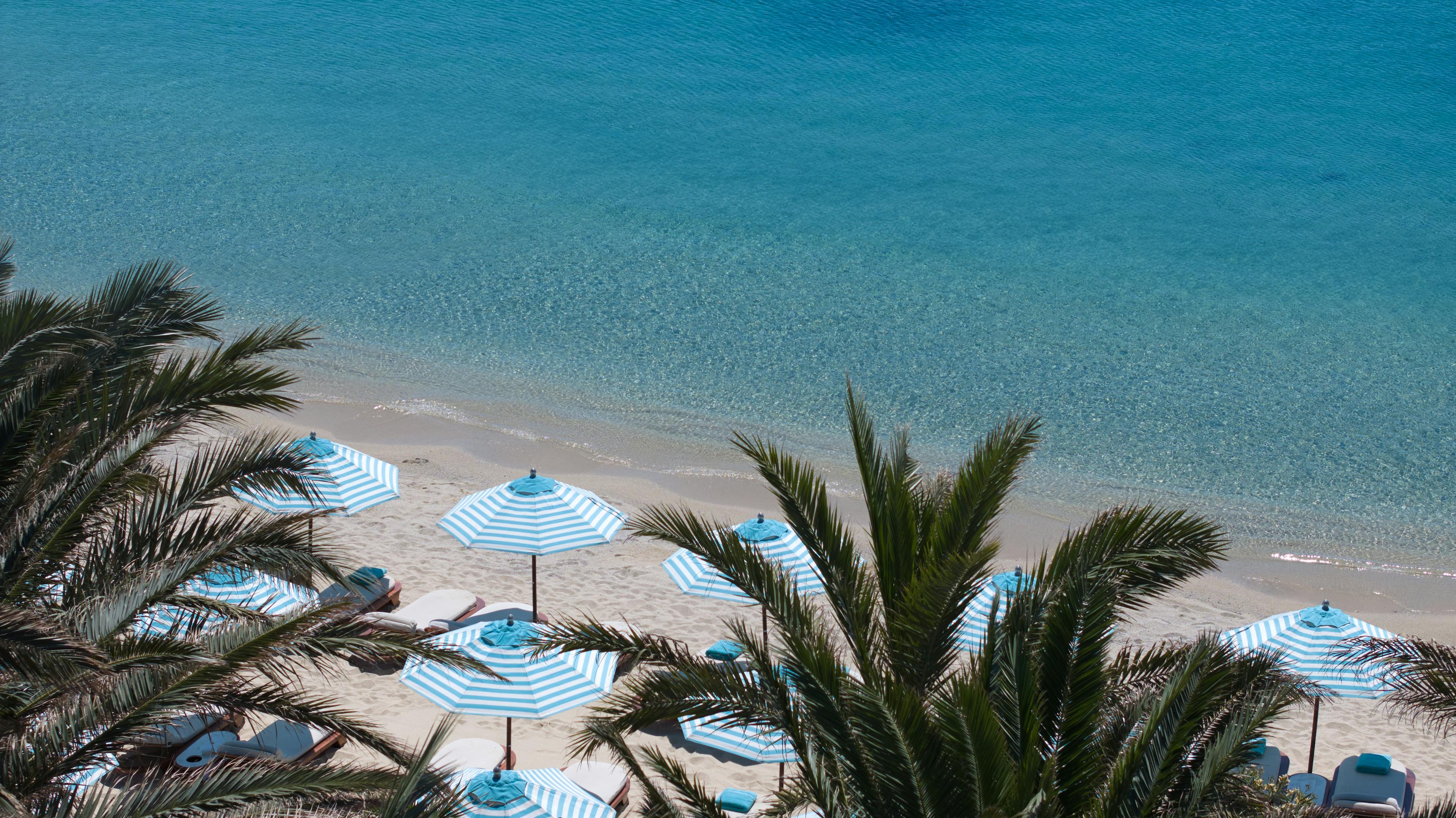 Palm trees, parasols, sand and sea at Psarou Beach