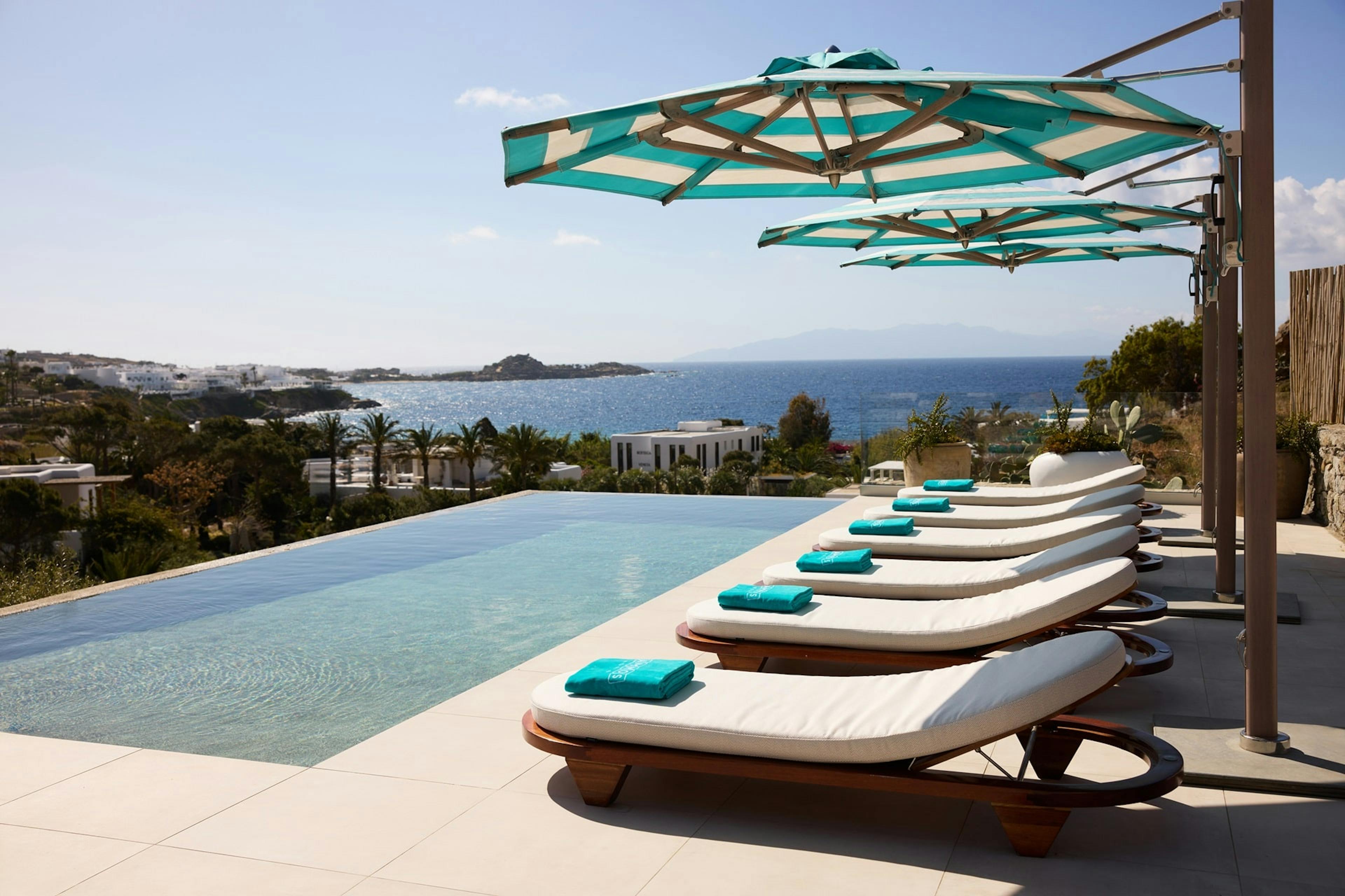 Sunbeds, parasol and pool against view of Aegean Sea