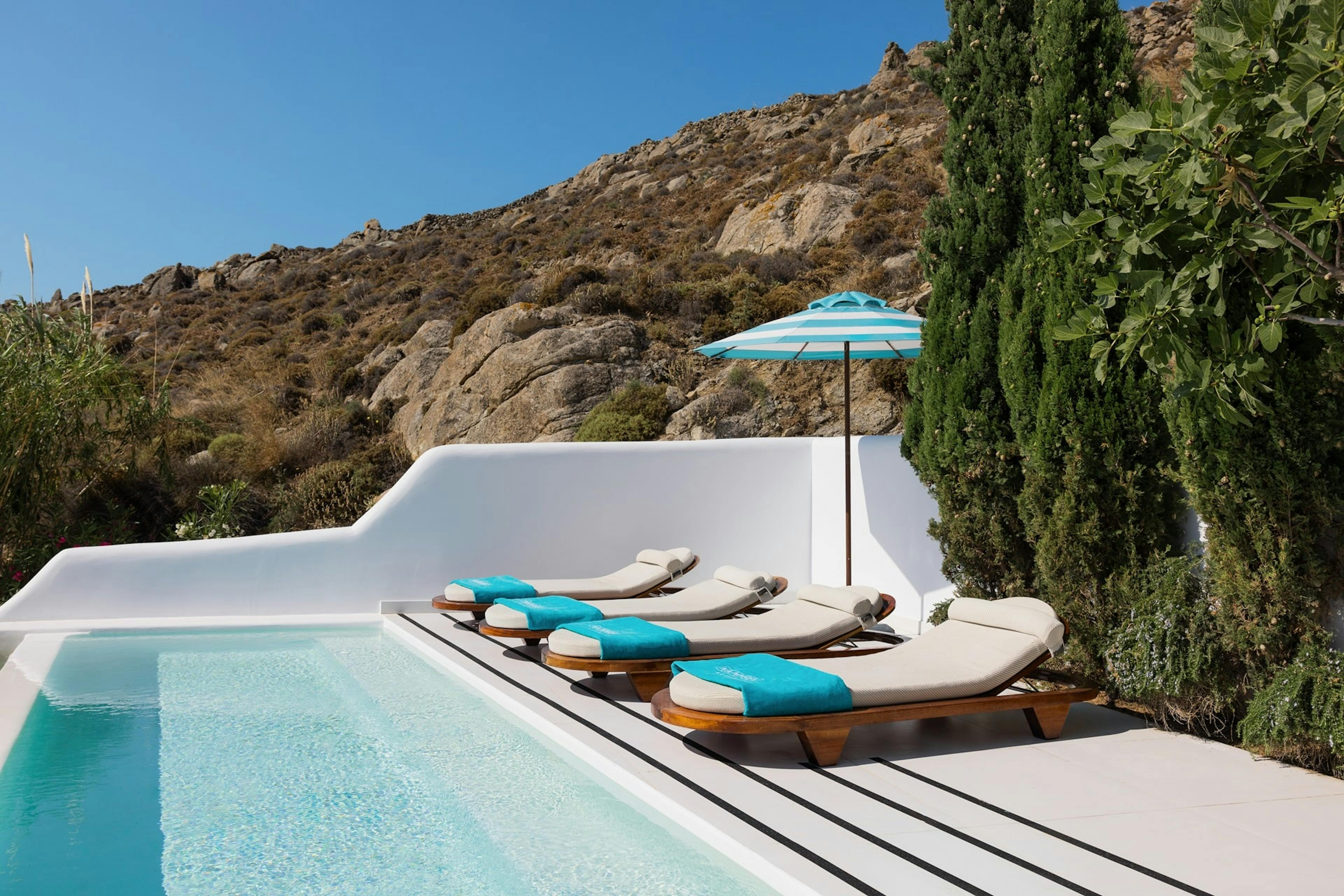 Sunbeds, parasol and pool against mountain in Mykonos