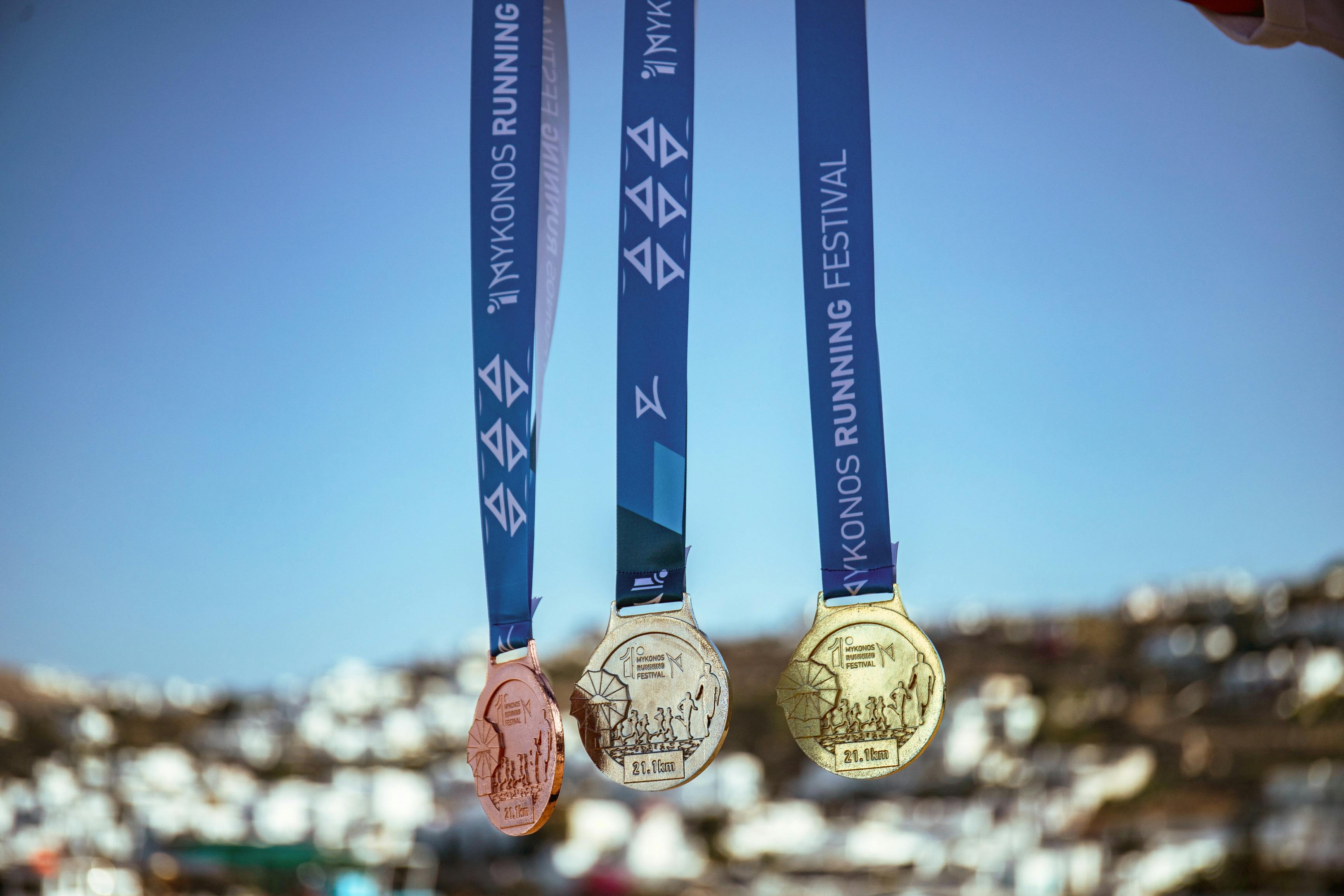 Gold Silver and Bronze medals against Mykonos backdrop 