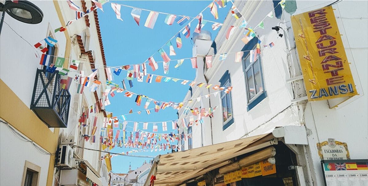 Several garlands of international flags hanging between buildings