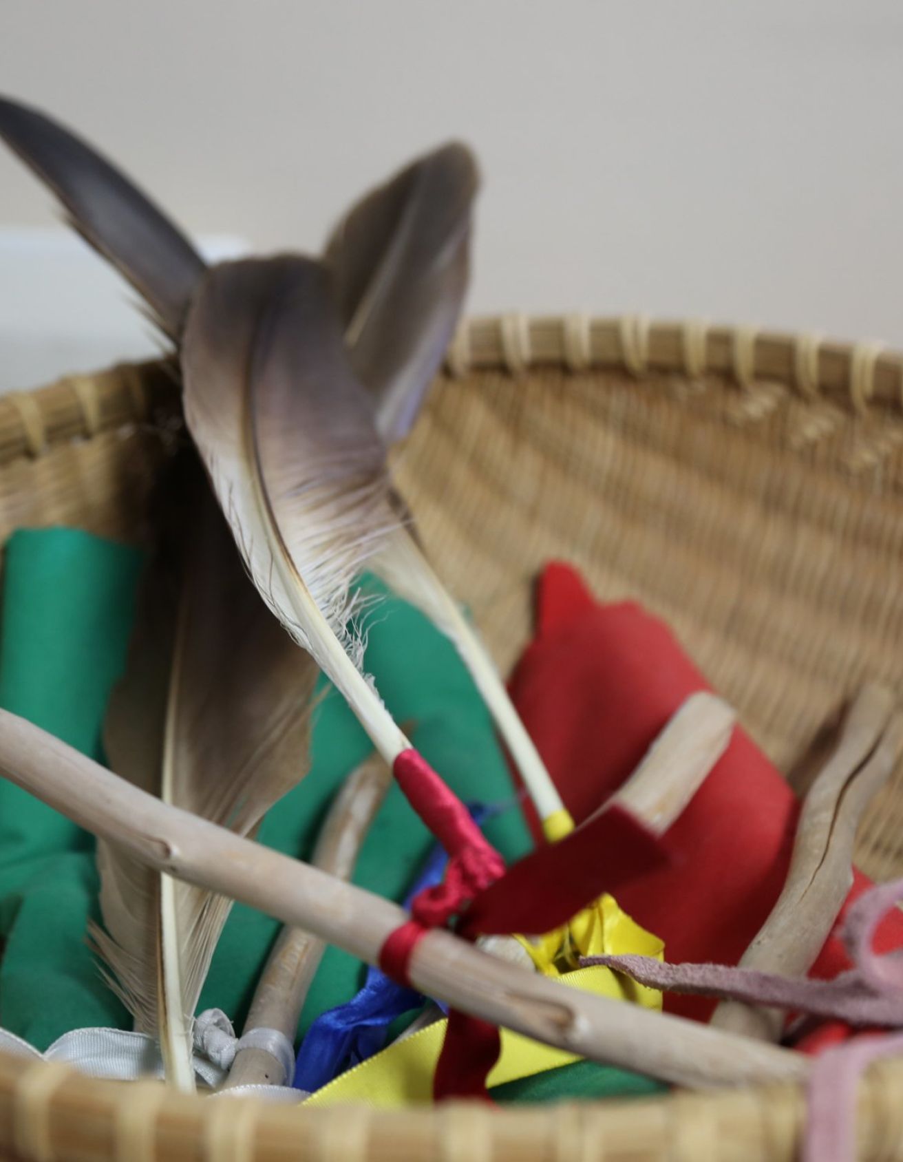 Close up of feathers wrapped in ribbons and multicoloured pieces of fabric in a wicker bowl