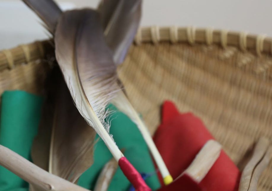 Close up of feathers wrapped in ribbons and multicoloured pieces of fabric in a wicker bowl