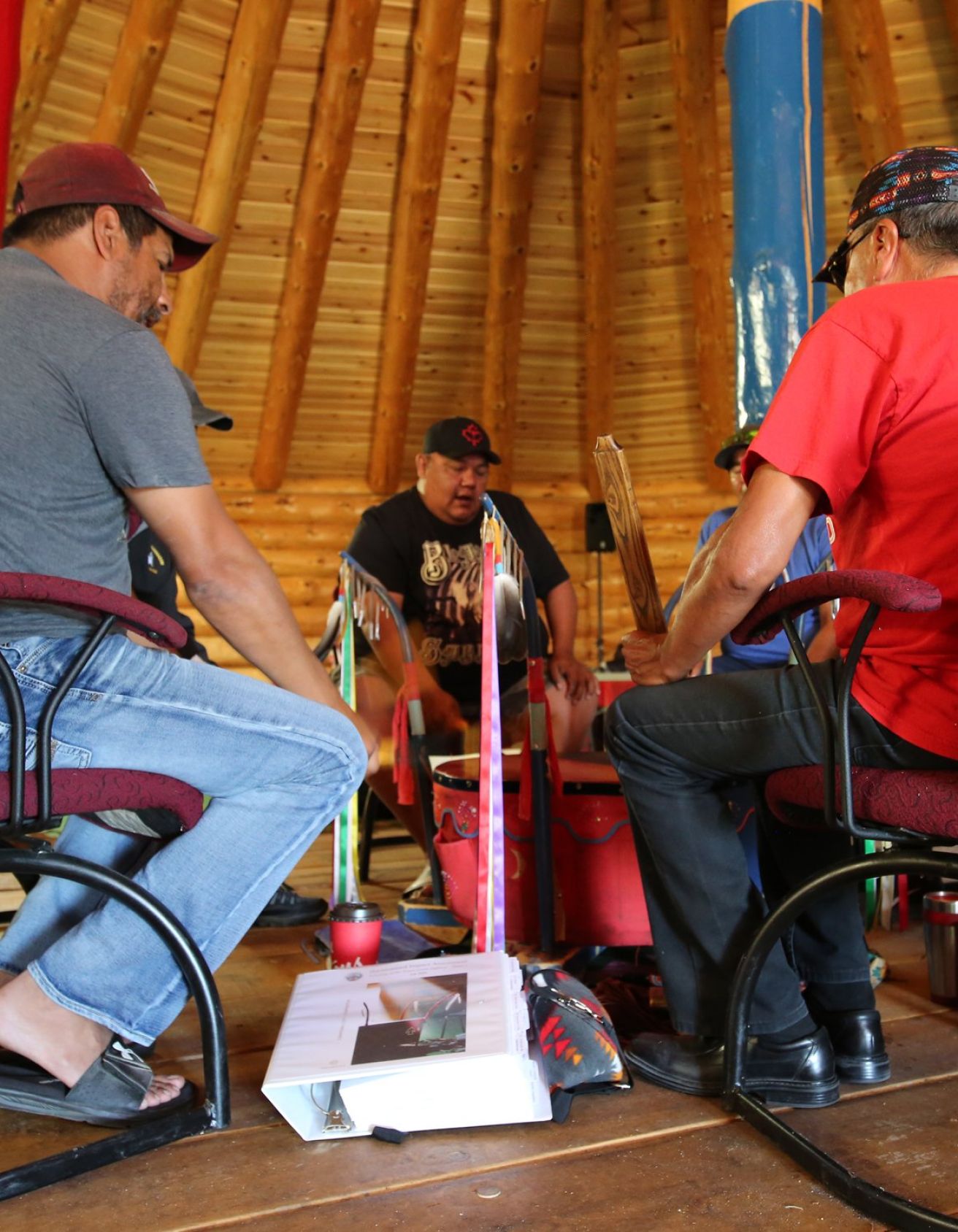 Five people sitting in a circle performing a drum ceremony