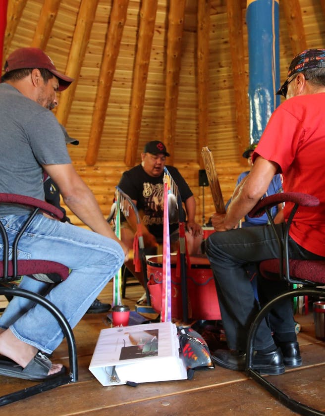 Five people sitting in a circle performing a drum ceremony