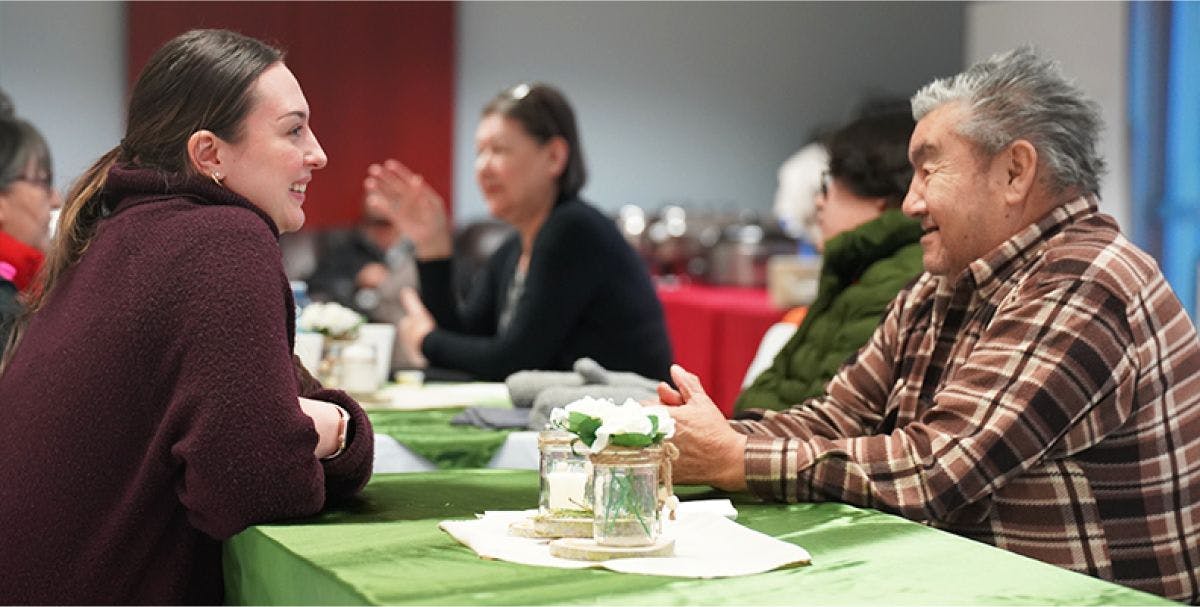 A woman and a man smile while in conversation at a table