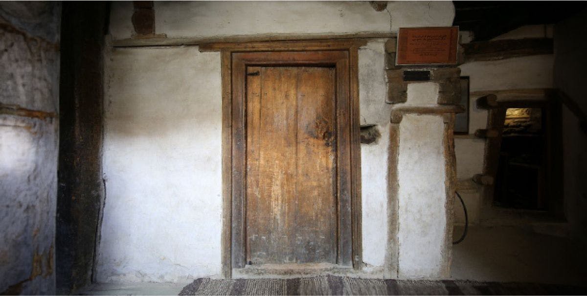 A very old wooden door in a dimly lit stone room