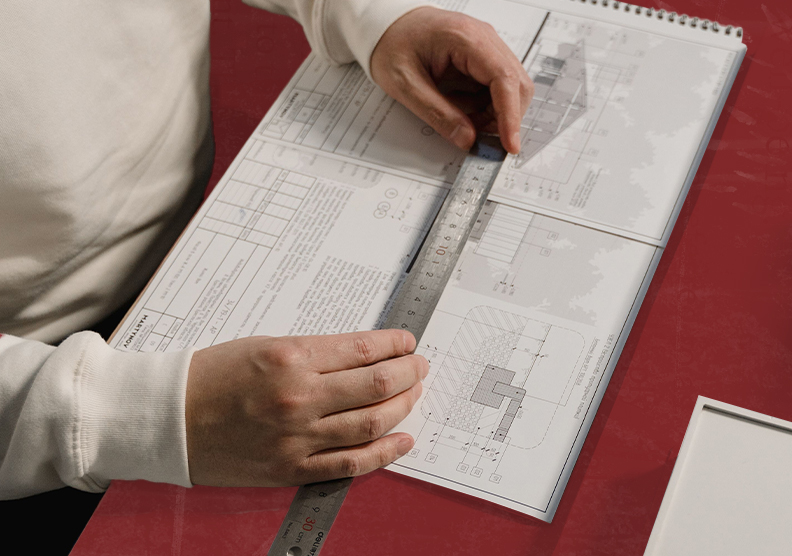 Person using a ruler to measure blueprints for a planning project