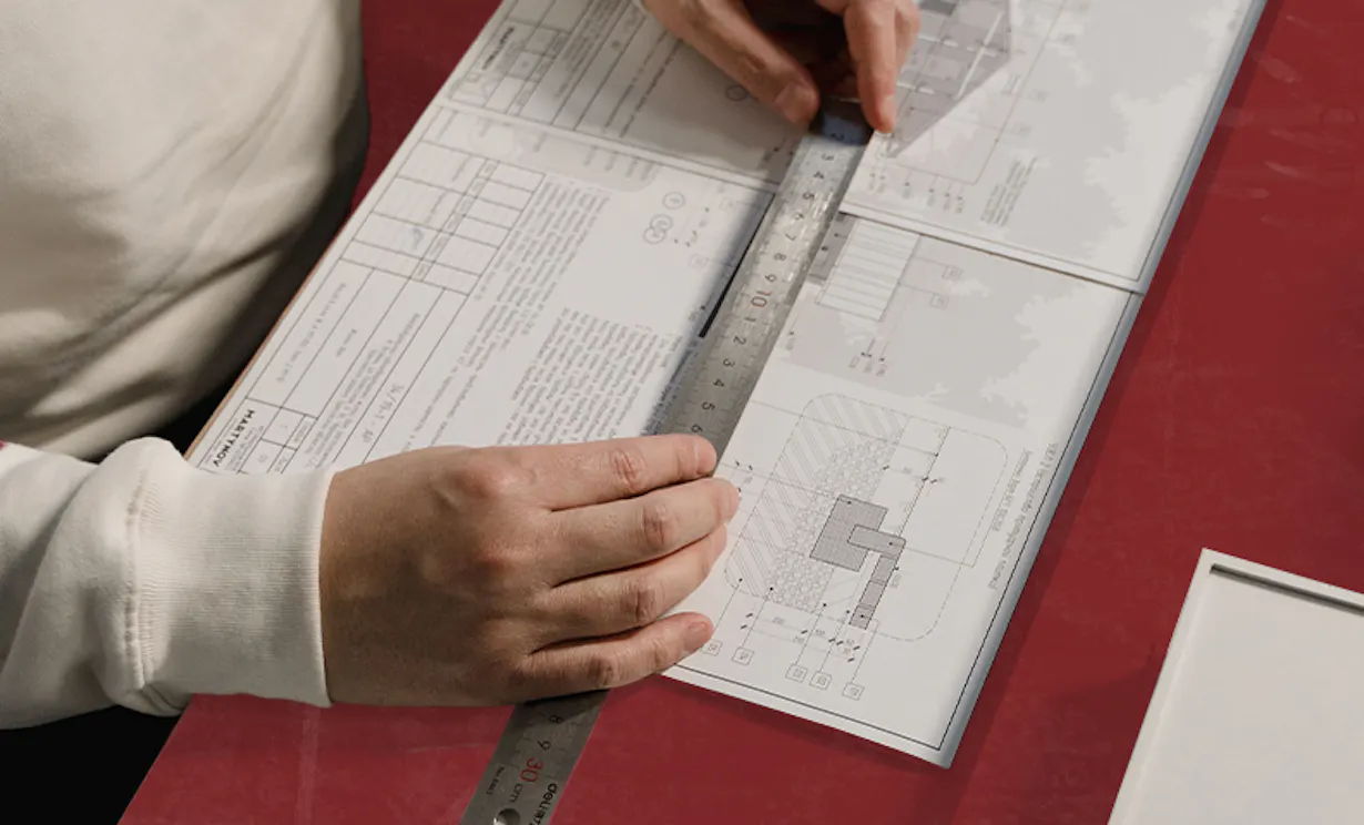 Person using a ruler to measure blueprints for a planning project