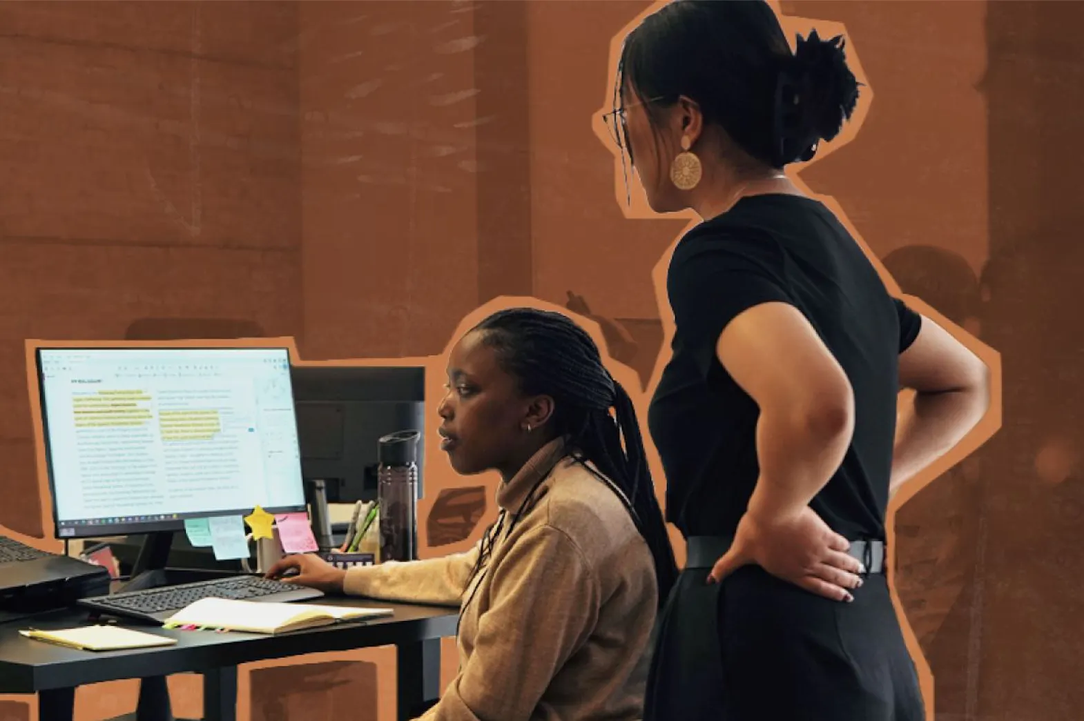 A woman standing and a woman sitting both looking at a computer screen