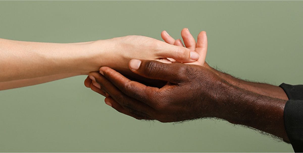 A pair of black hands hold a pair of white hands
