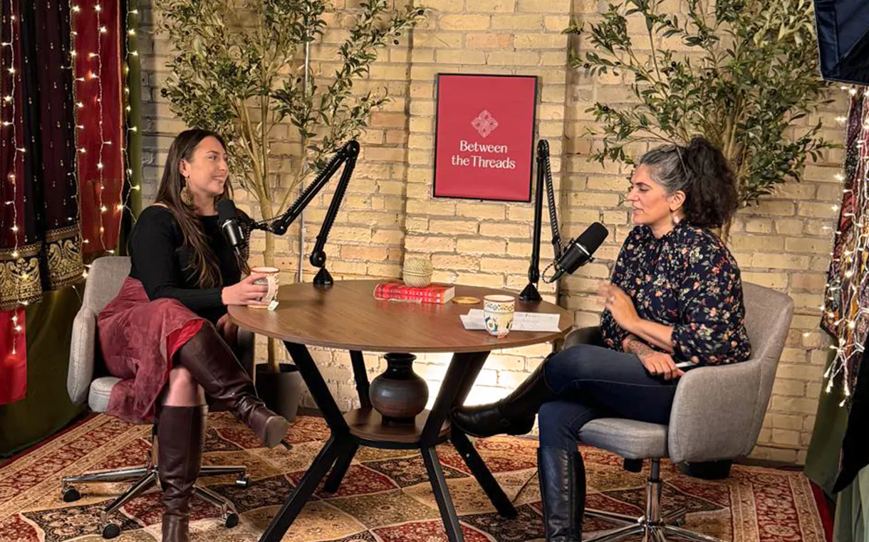 Two women sitting at a table in a studio recording a podcast