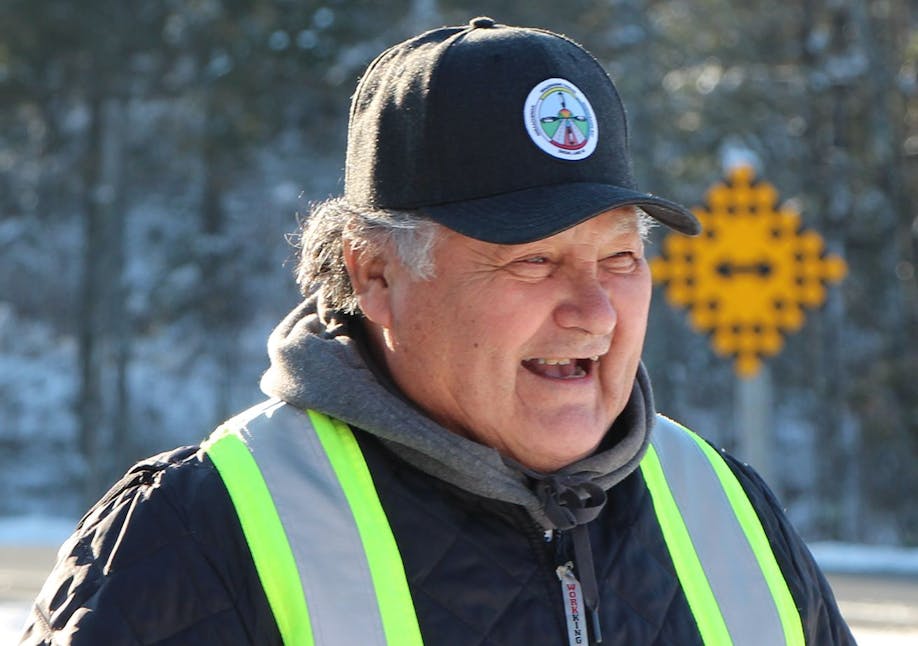 Elderly man smiling while wearing a safety jacket and ball cap