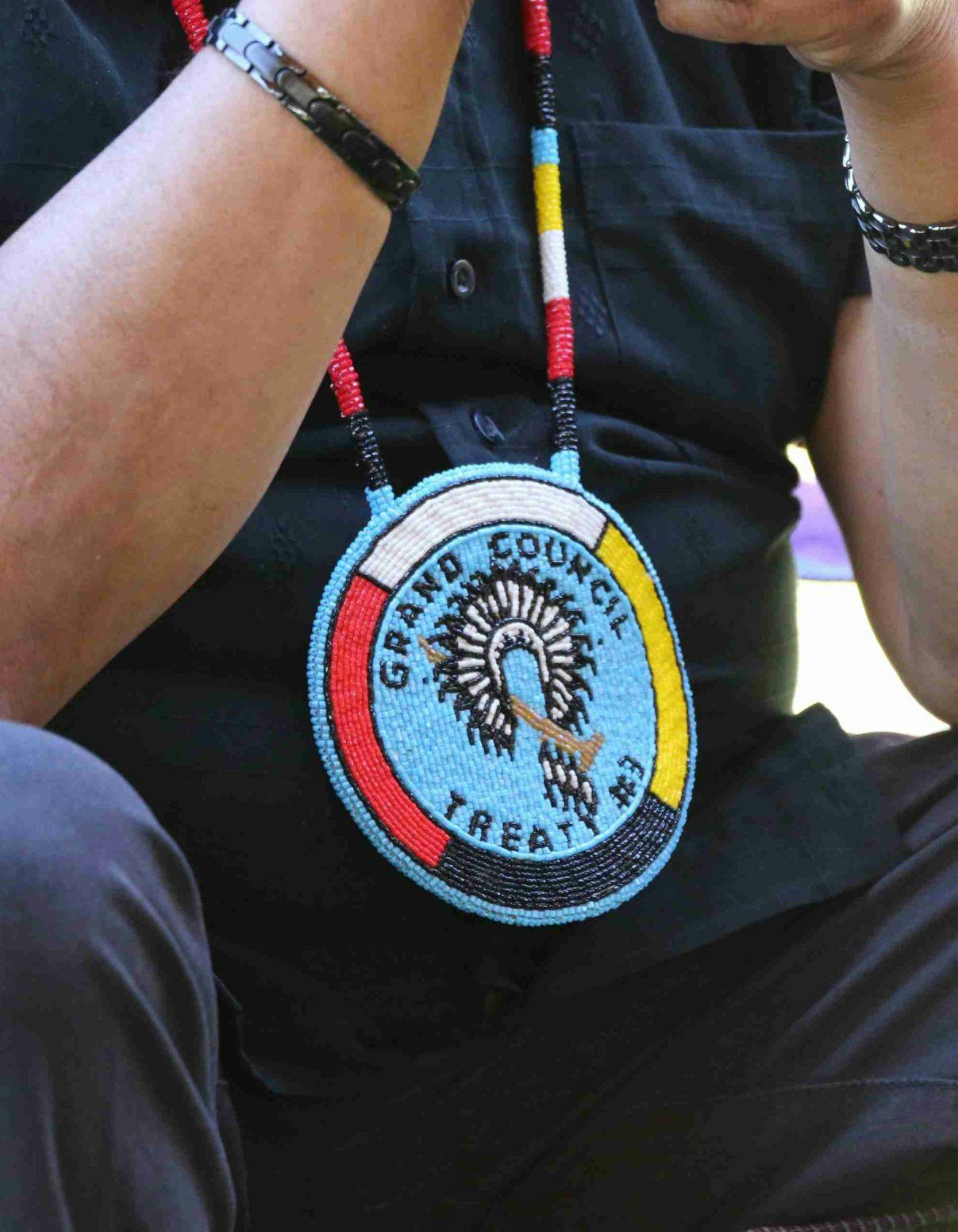 Close up of a man's torso who is wearing a Grand Council Treaty #3 beaded medallion