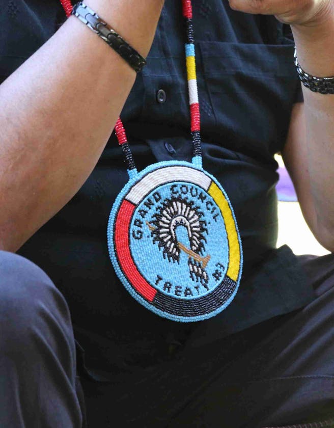 Close up of a man's torso who is wearing a Grand Council Treaty #3 beaded medallion