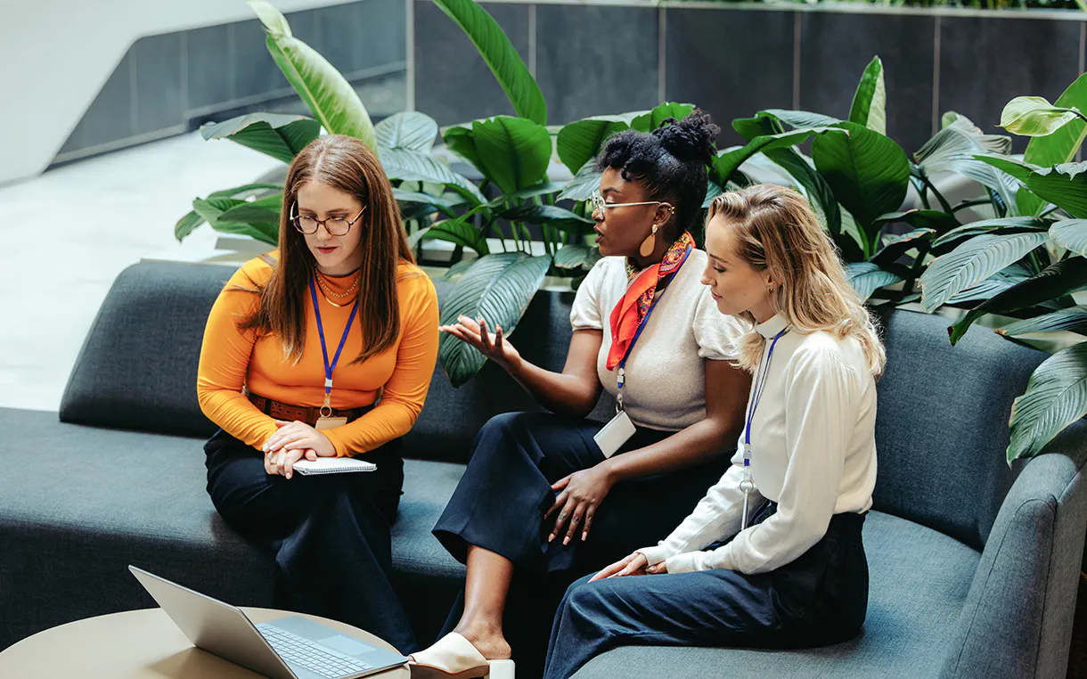 Three diverse team members collaborating over a laptop to establish consensus-based governance and build operational trust in a modern workspace.