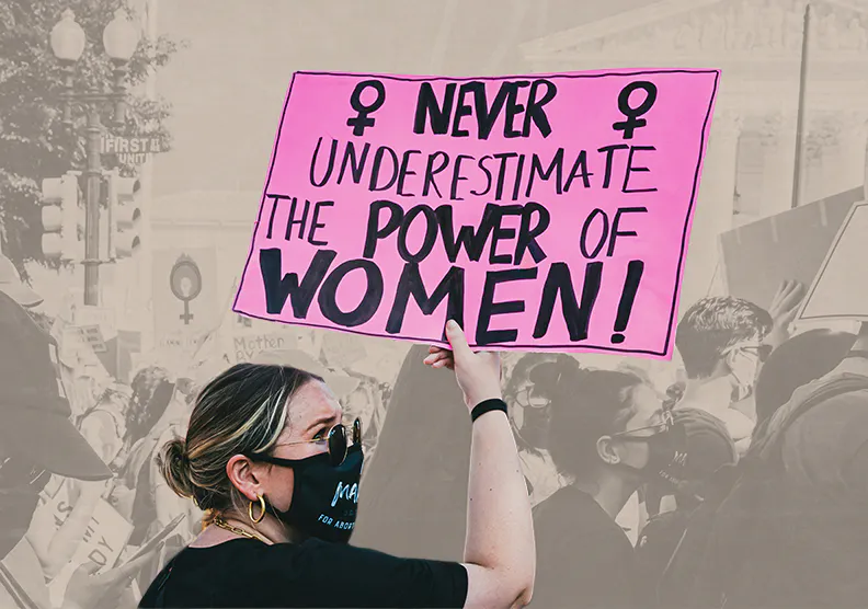 A woman holds a sign at a protest reading 'Never underestimate the power of a women!'