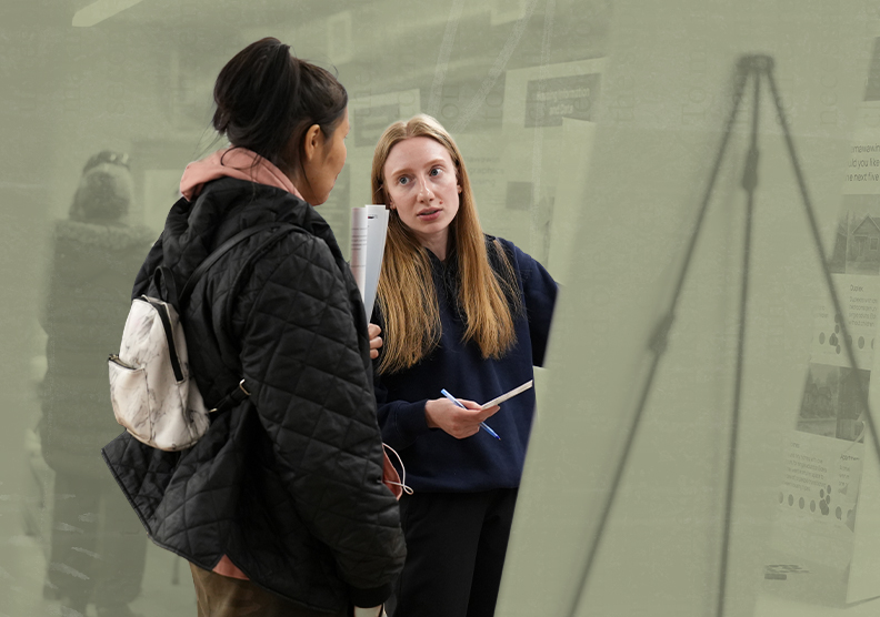 Two people talk in front of a climate action board at a community engagement