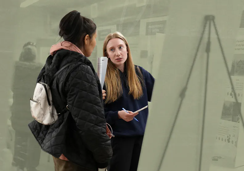 Two people talk in front of a climate action board at a community engagement