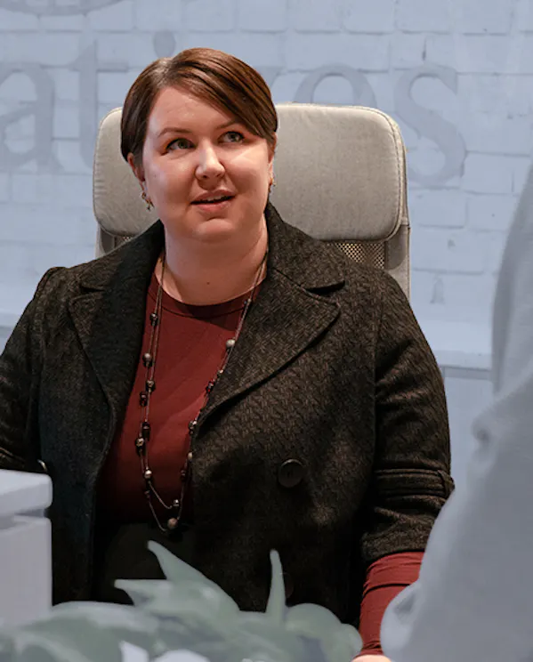 A woman sits at a desk talking to a coworker
