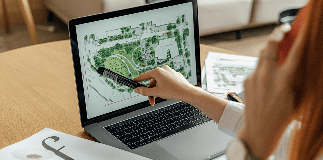 A woman using her laptop to create a detailed landscape drawing.