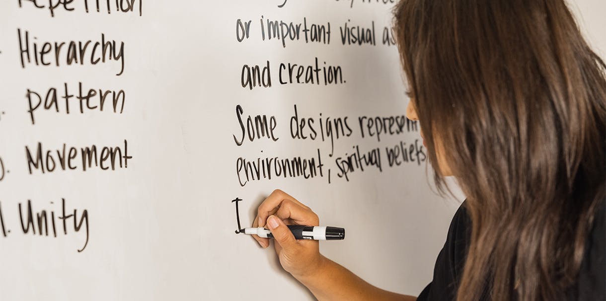 Indigenous women writing Graphic Design terms on a whiteboard