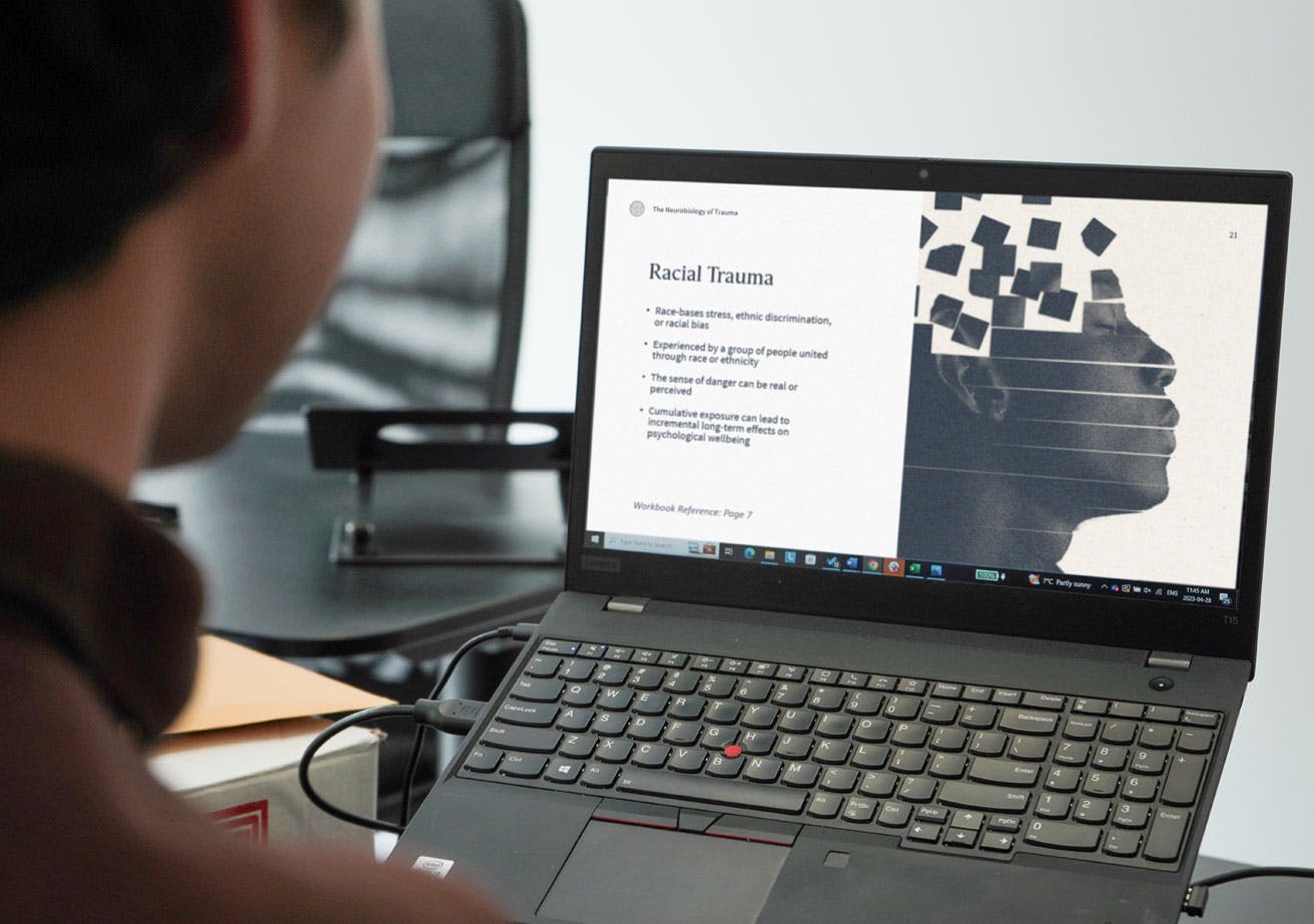 A man looks at a laptop screen featuring a presentation slide