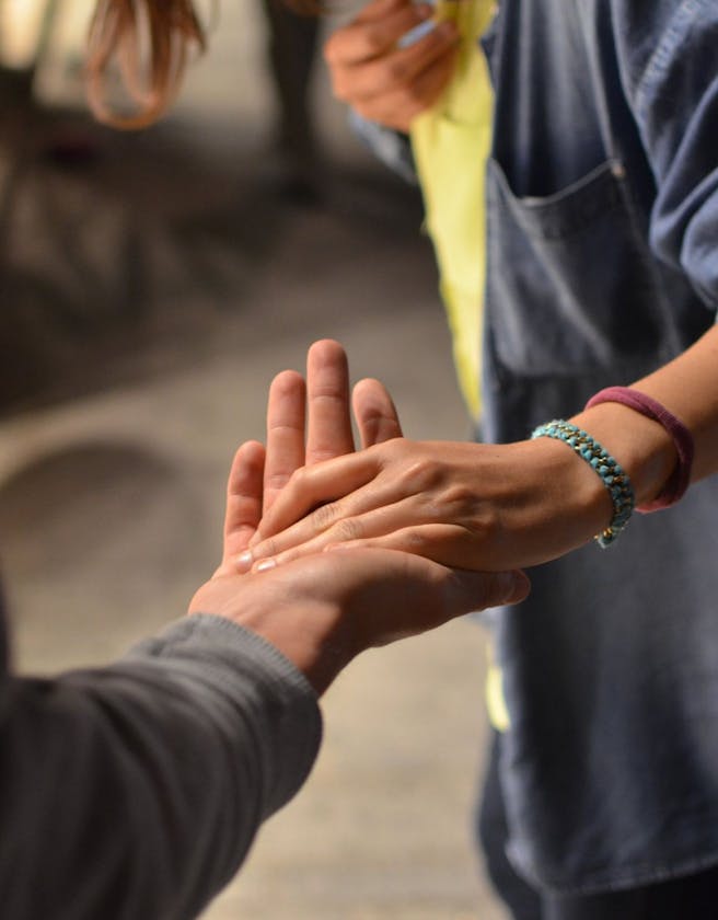 Close up shot of one person placing their hand in the palm of another