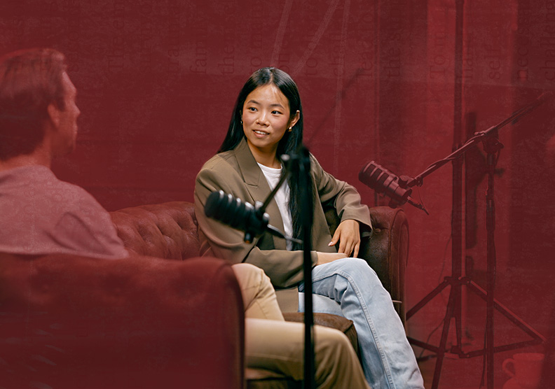 A woman sits on a couch recording a podcast in a studio