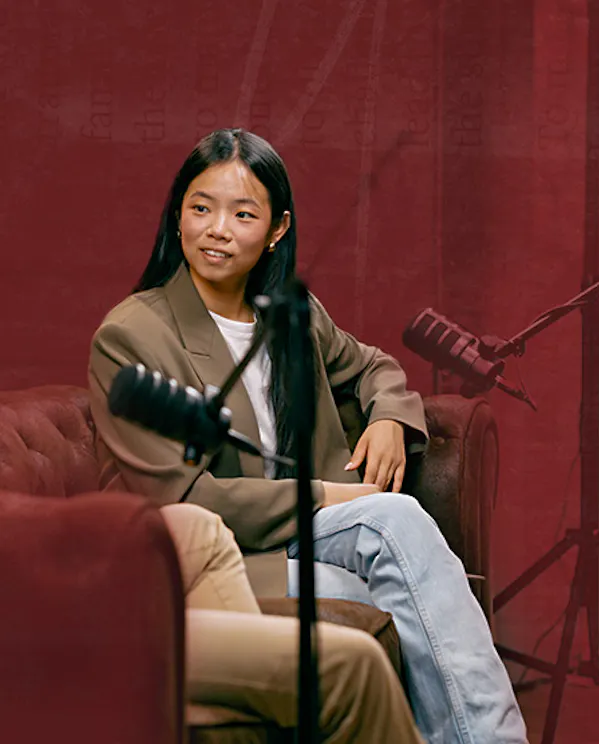 A woman sits on a couch recording a podcast in a studio