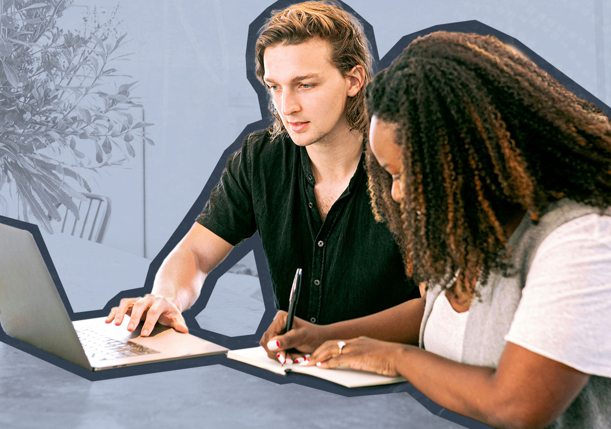 A man uses a laptop while a woman writes in a notebook beside him at a table