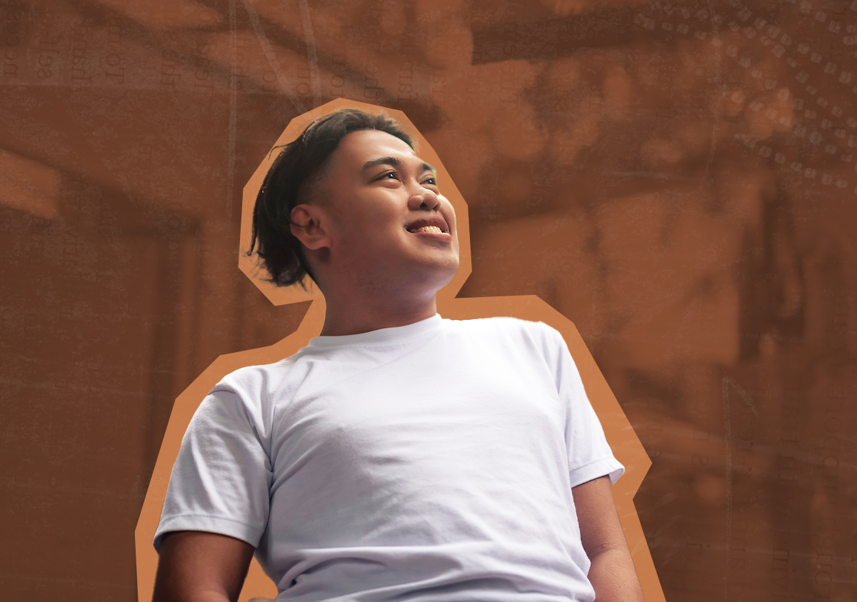 A smiling Filipino man wearing a white t-shirt looks off into the distance.