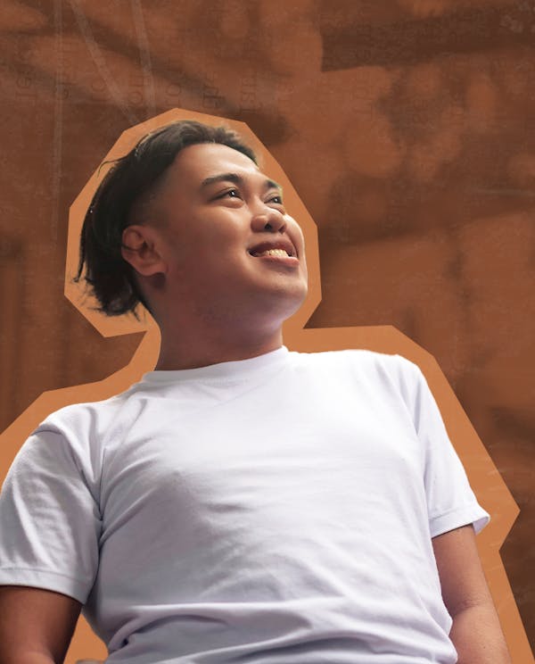 A smiling Filipino man wearing a white t-shirt looks off into the distance.
