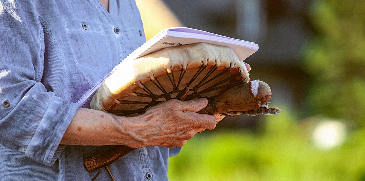A person holding a drum and notebook with both hands.