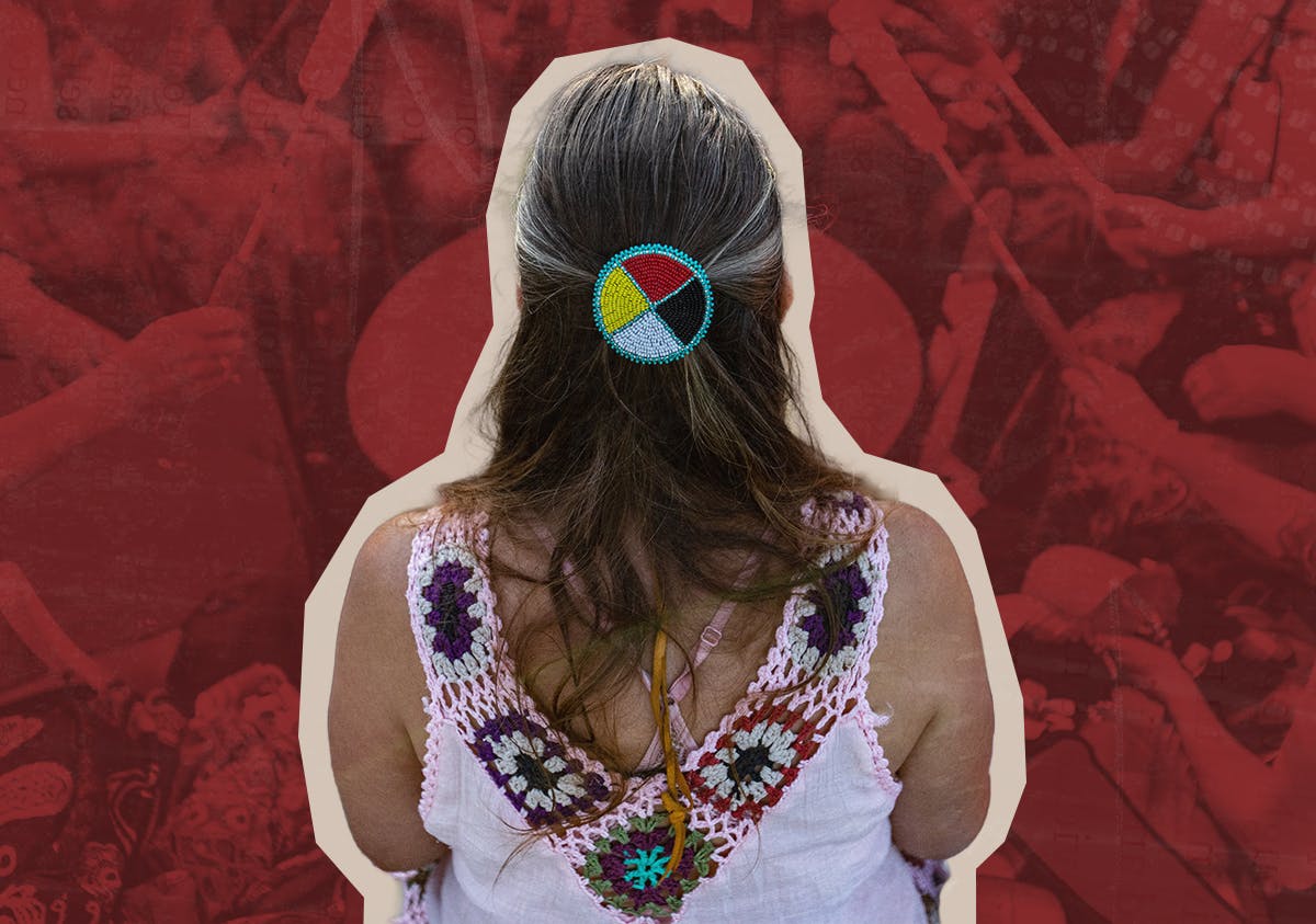 A woman wearing a medicine wheel headband sits in a drumming circle