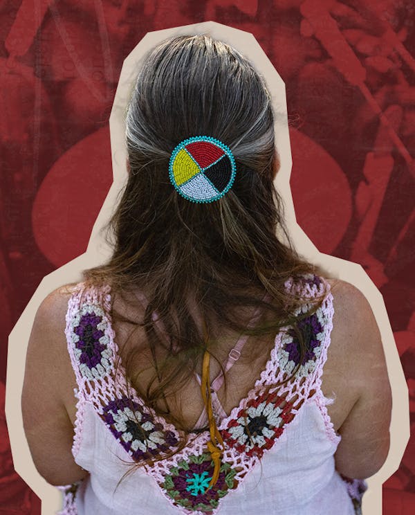 A woman wearing a medicine wheel headband sits in a drumming circle