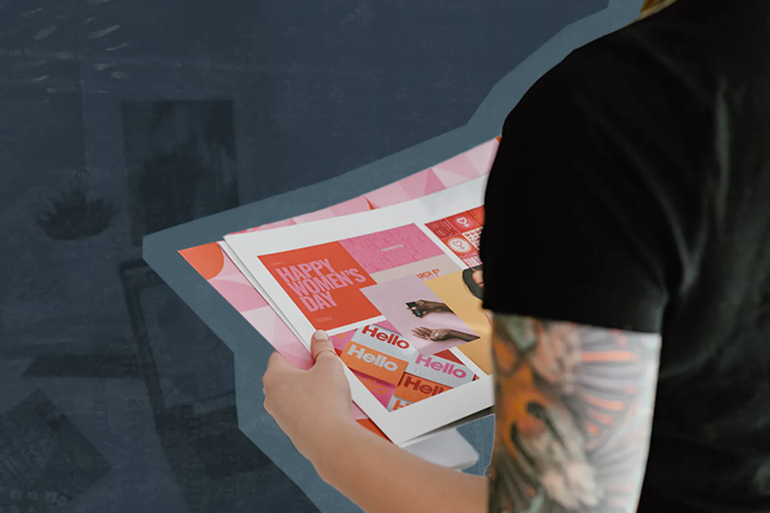 A woman holds papers with graphic design examples printed on them