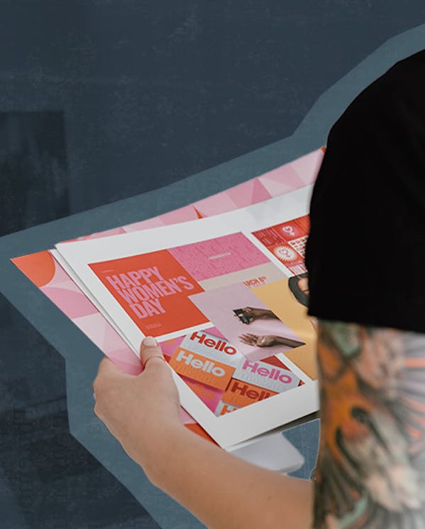 A woman holds papers with graphic design examples printed on them