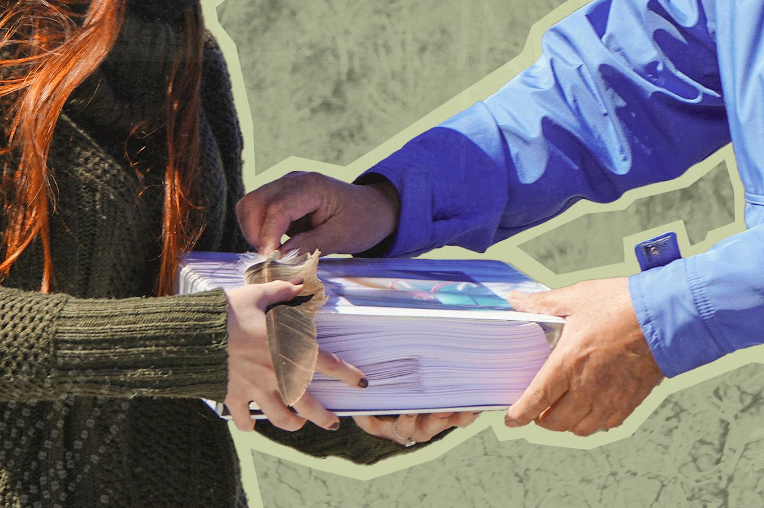 People trading a large stack of booklets and a feather with each other