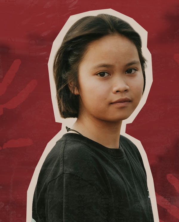 A young Indigenous girl looks at the camera. Behind her is a natural landscape and red handprints.