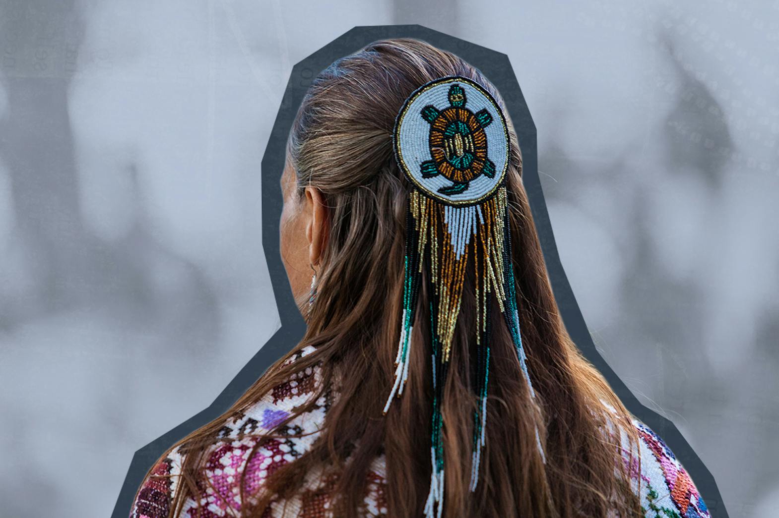 The back of an Indigenous woman's head with a beaded turtle medallion in her hair