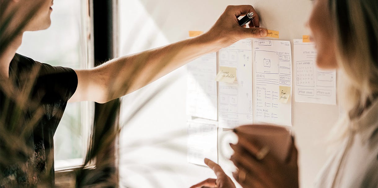 People collaborating and placing sticky notes on a board