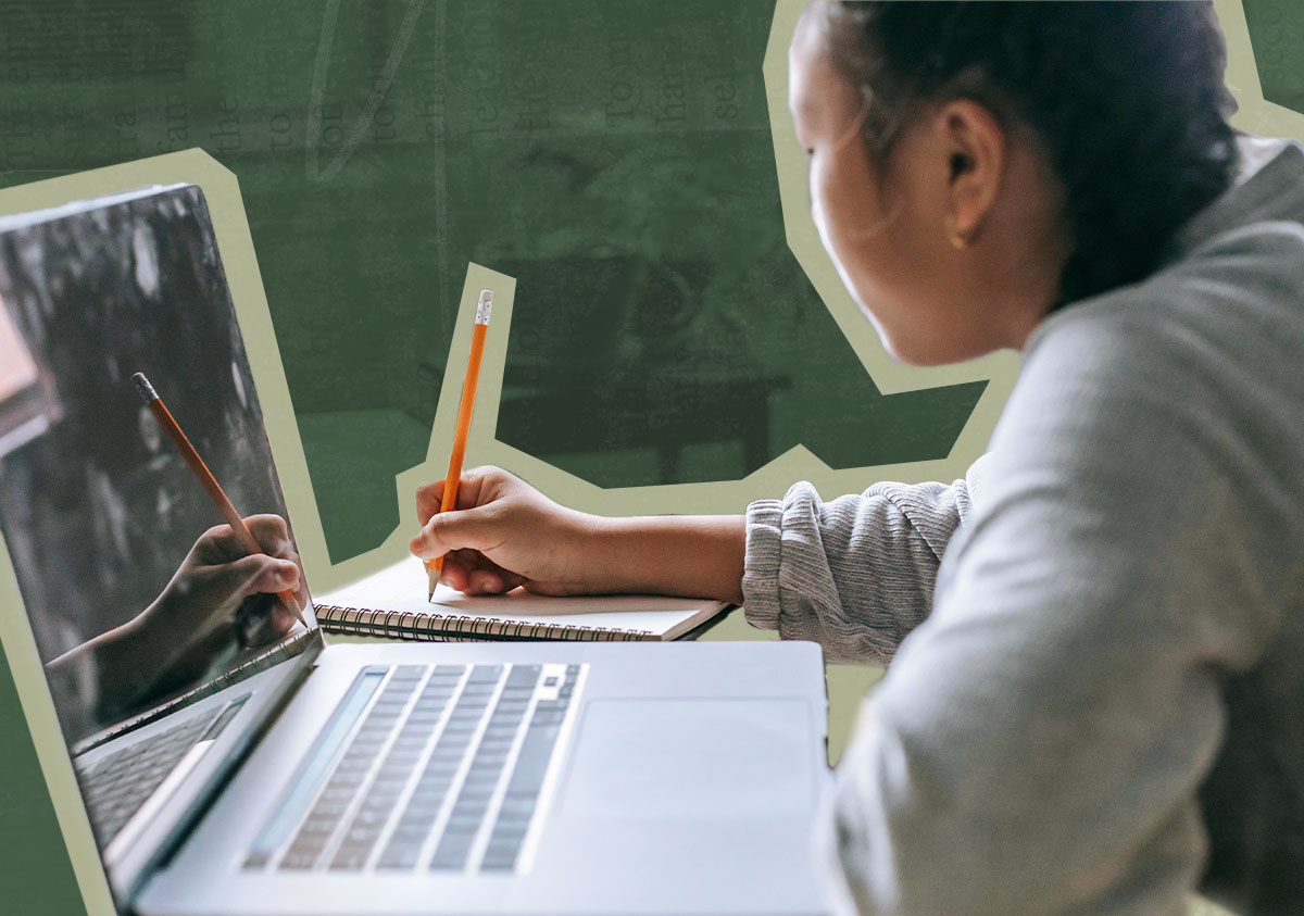 A woman writing on a notebook with a pencil. A laptop is sitting on the desk next to her
