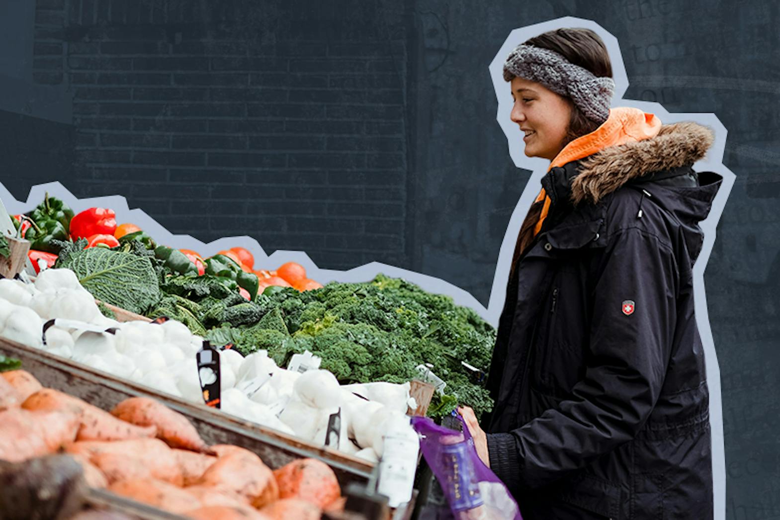 A woman stands outside looking at a variety of fresh produce at a farmers market