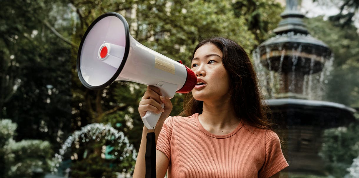 A women stands outside speaking into a megaphone