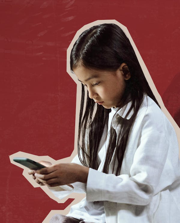 A young girl looks down at a phone screen