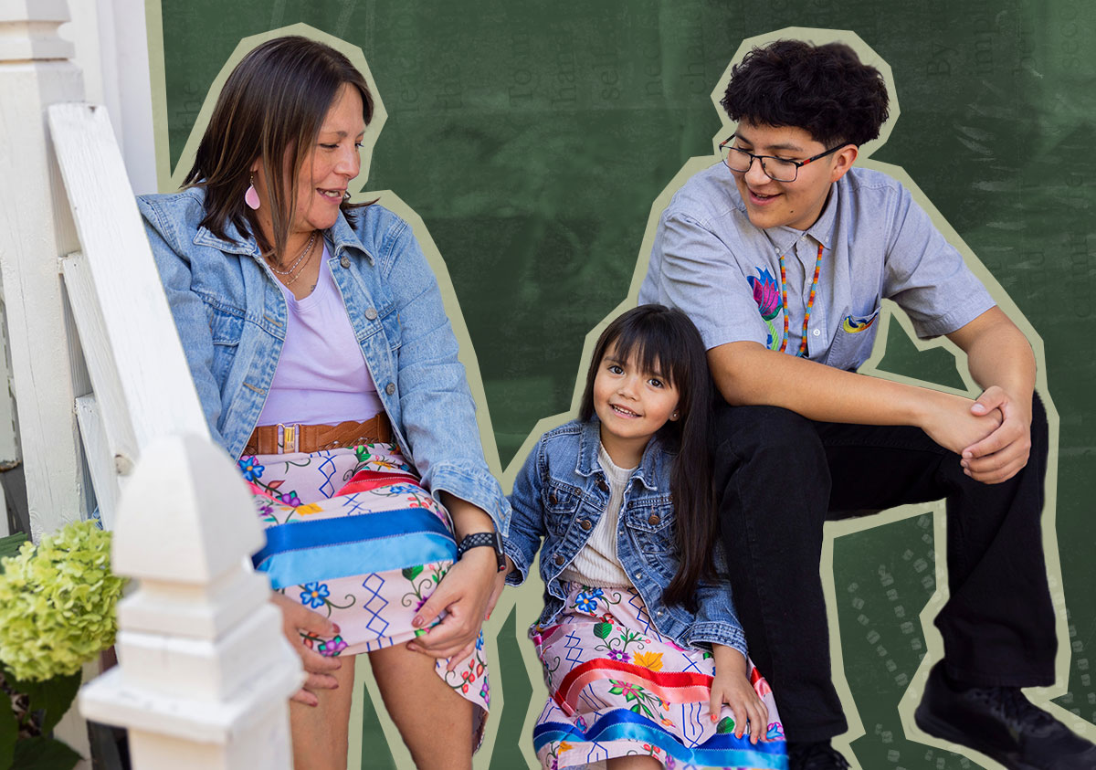 An Indigenous family sits on a porch smiling at each other. The women are wearing colourful ribbon skirts.